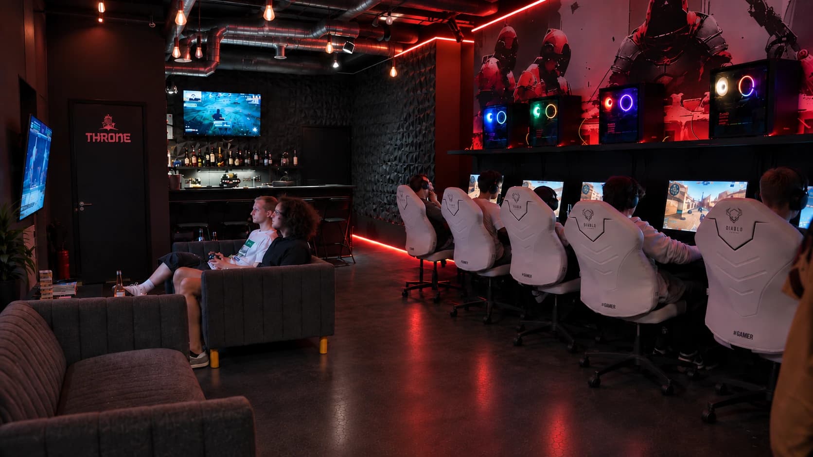 Sala klubu Project Armor w całości – kanapy, rząd stanowisk i bar w głębi